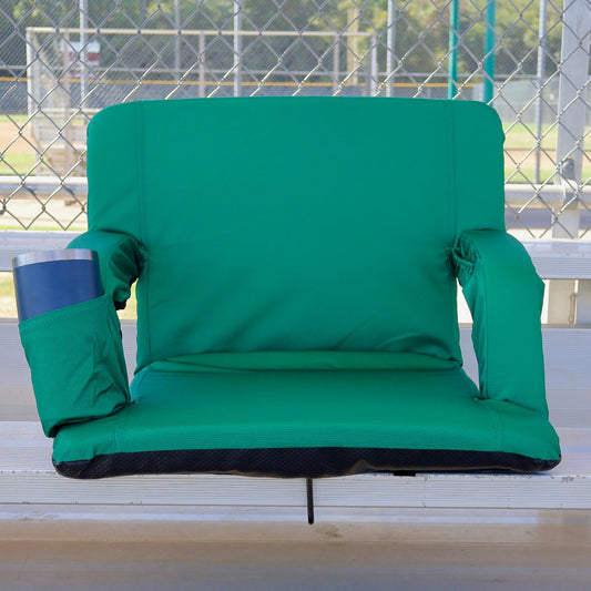 A green stadium-style spectator chair with padded armrests and a side cup holder, shown on outdoor bleachers with a chain-link fence in the background.